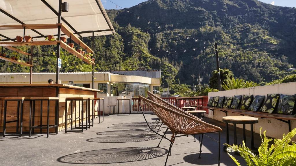 a patio with chairs and tables and a mountain at Crater Eruption Backpacker Hostel in Baños