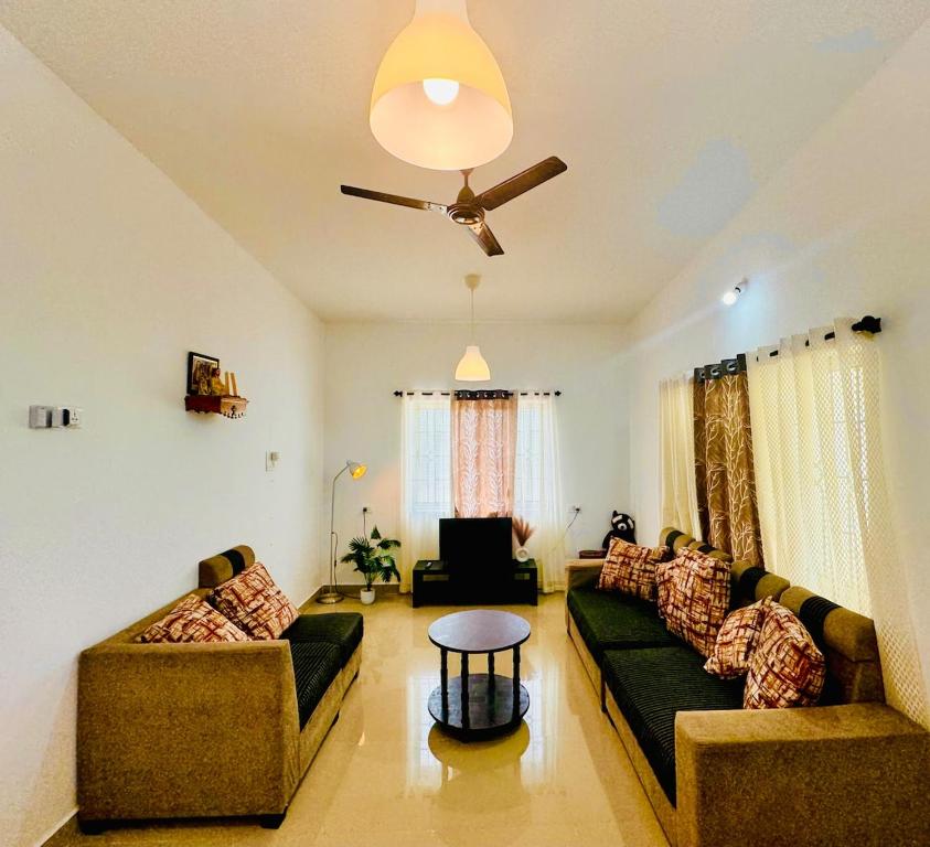 a living room with two couches and a ceiling fan at Si' Casa in Mandrem