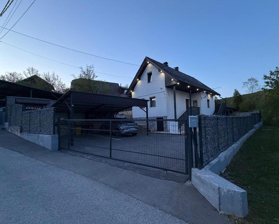 a fence in front of a house with a garage at Apartments Sertic 4 stars in Poljanak
