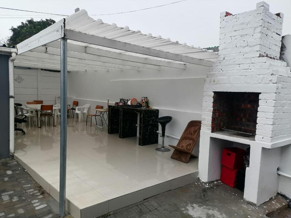 a white patio with a fireplace and a table at 36 the trout lodge in Goodwood