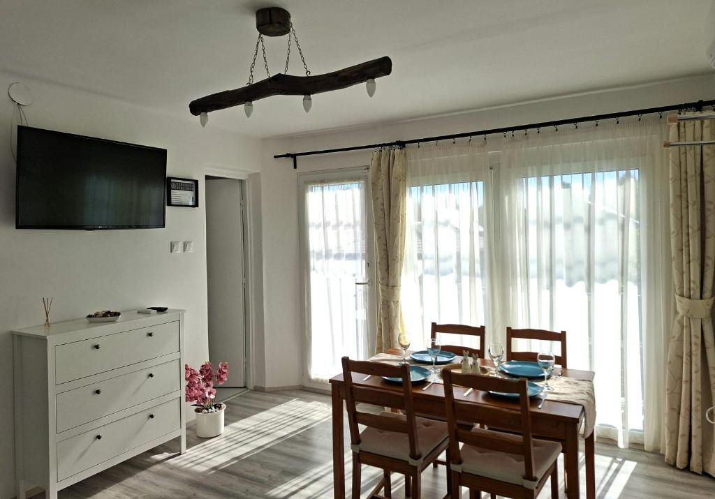 a dining room with a table and chairs and windows at Corddora Apartman in Mezőkövesd