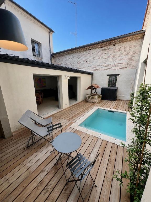 a wooden deck with a table and chairs next to a pool at La Maison des Filles in Agen