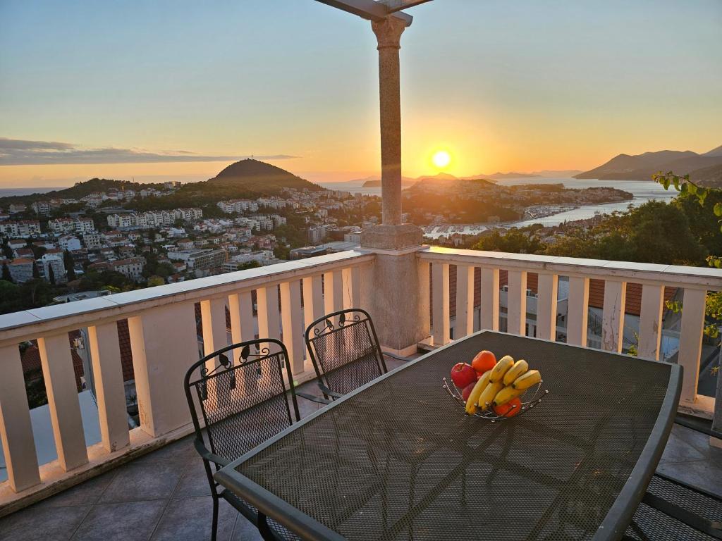 a bowl of fruit on a table on a balcony with the sunset at Guest House Banana in Dubrovnik