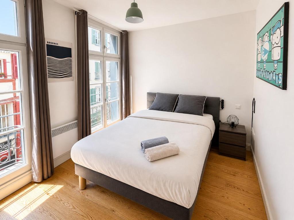 a bedroom with a large white bed with two windows at Chambre moderne au Petit Bayonne chez particulier in Bayonne