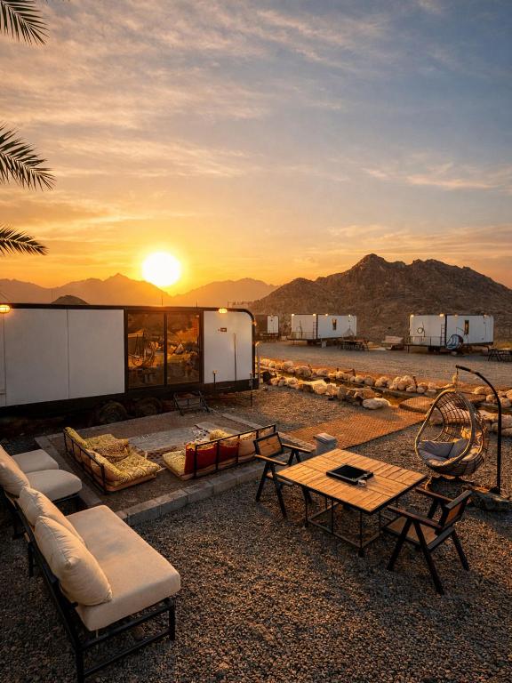 a patio with a table and chairs and the sunset at The Out Resort in Sinādil