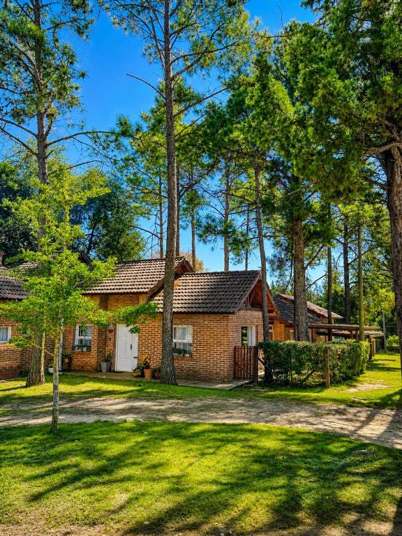 a brick house with a yard and trees at Complejo Aldea Champaqui in Villa General Belgrano