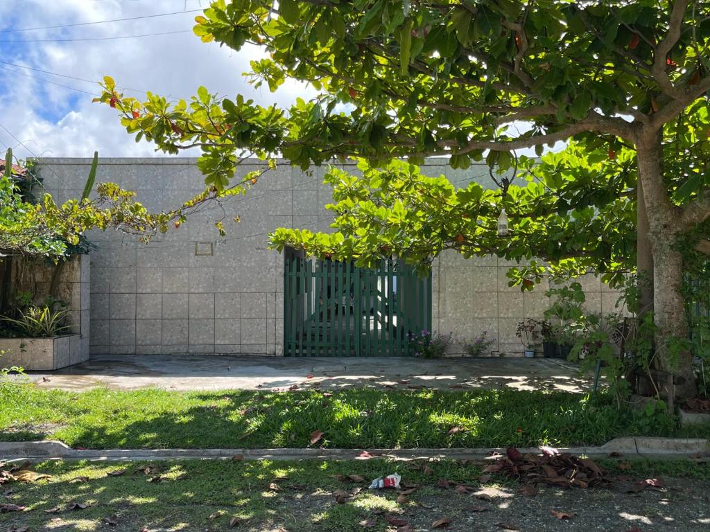 a building with a green gate and a tree at Pousada Açaí in Ilha Comprida