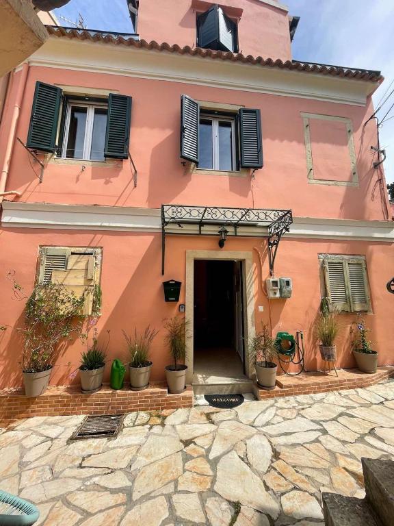 a pink house with potted plants in front of it at Vilia Port House- Corfu Centre in Mantoúkion