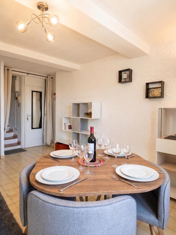 a dining room with a table with glasses and a bottle of wine at Charmant T3 au centre de gréoux les bains in Gréoux-les-Bains