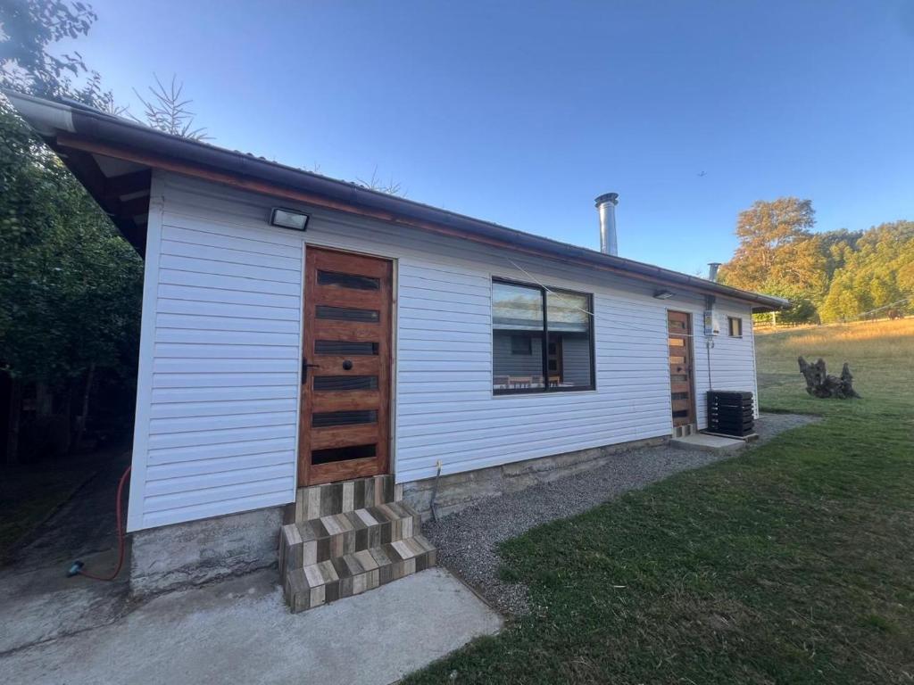 a small white house with wooden doors on a yard at Lanco in Lanco