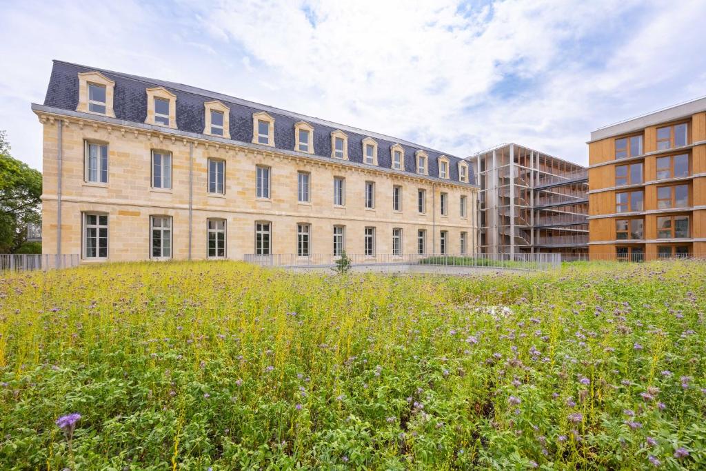 a large building with a field in front of it at BABEL COMMUNITY Hôtel Bordeaux in Bordeaux