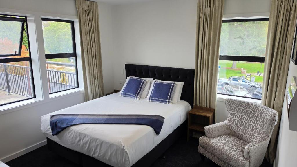 a bedroom with a bed and a chair and windows at Lake Taupo Hotel in Taupo