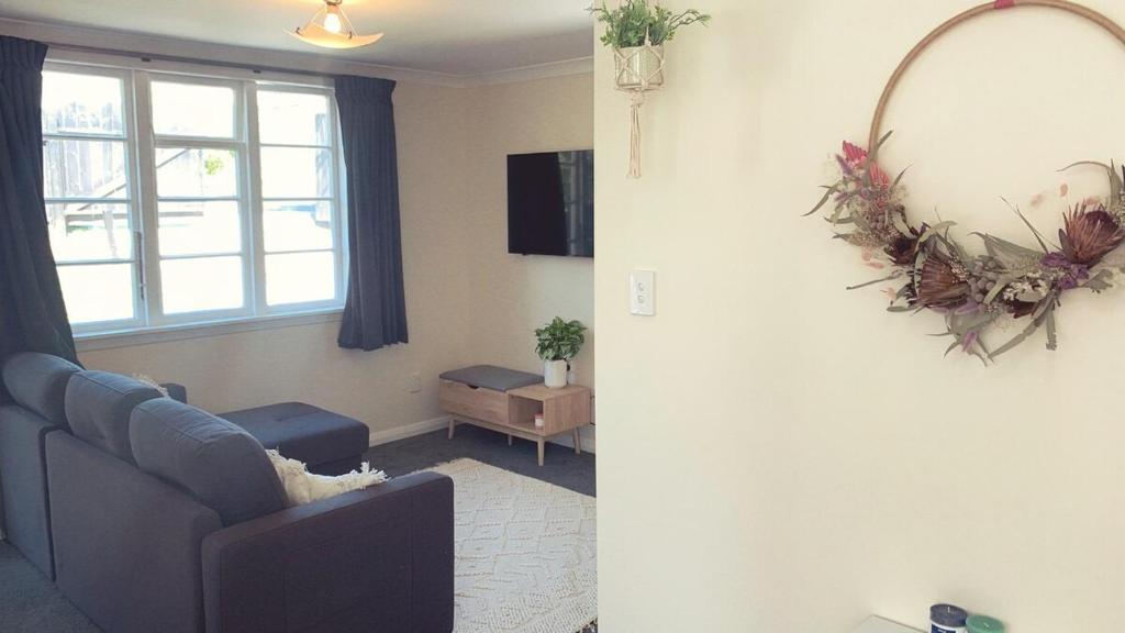 a living room with a couch and a mirror at Sun kissed beach haven in Waitarere