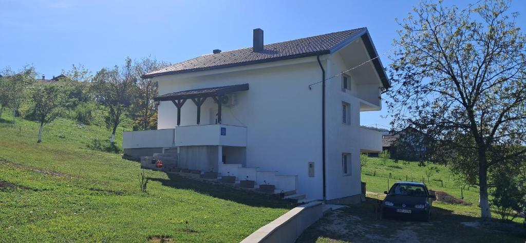 a small white building with a car parked next to it at Japodska Oaza in Bihać