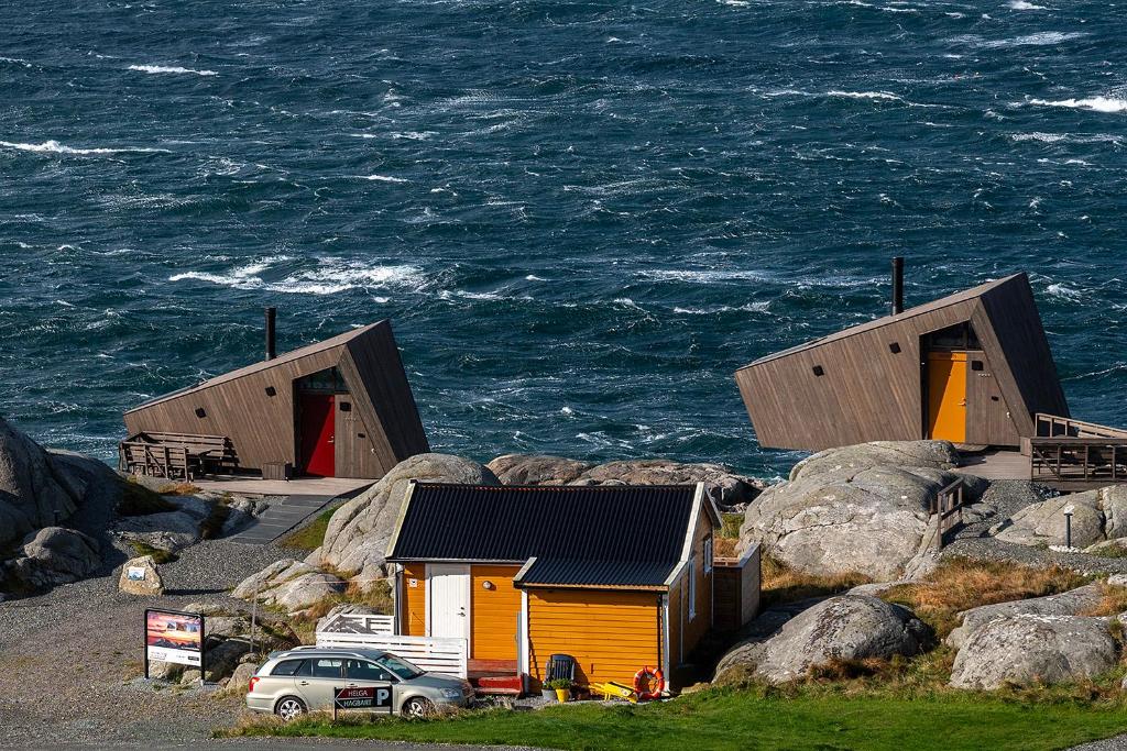 two buildings on the rocks near the ocean at Sandhåland Camping Hytte nr 7 in Sandhåland