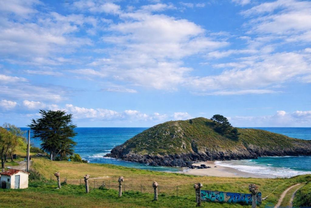 a small island in the ocean next to a beach at Apartamento Barro Playa in Barro de Llanes