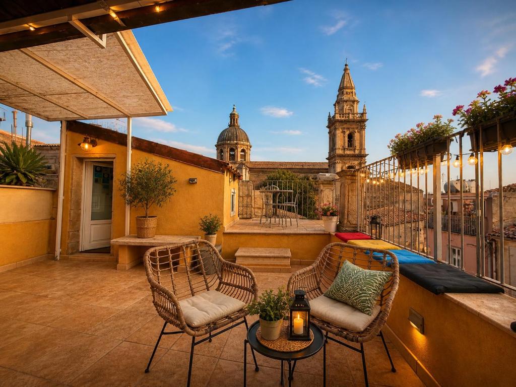 a balcony with two chairs and a table and a building at Suites Sangiovanni in Ragusa