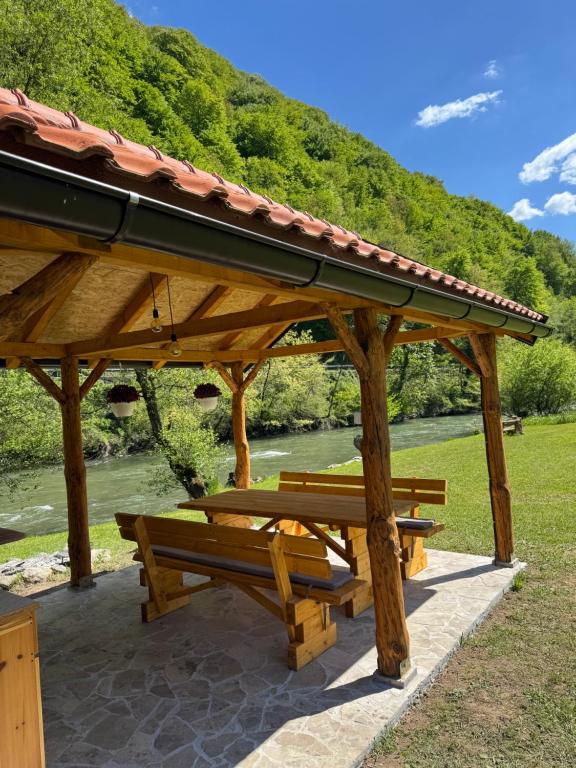 a wooden pavilion with benches in front of a river at River Resort Vinac Jajce in Jajce