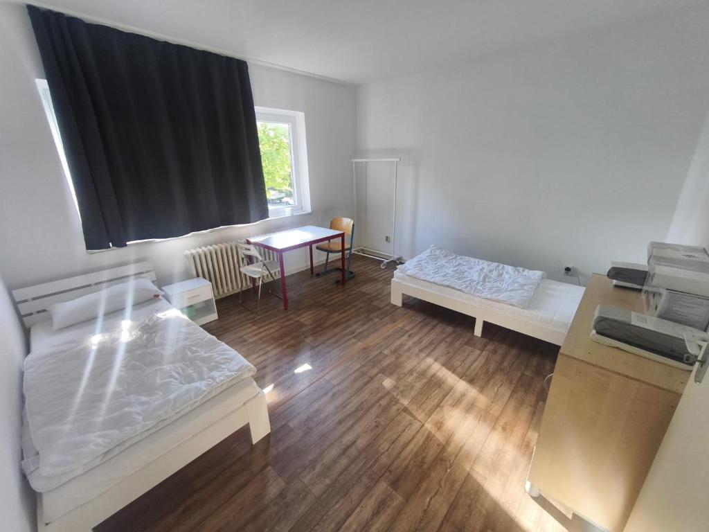 a room with two beds and a table and a window at GM Zimmervermietung in Hamburg