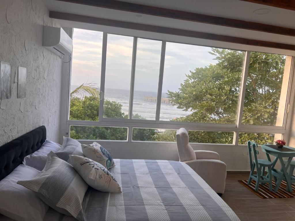 a bedroom with a bed and a view of the ocean at Puerto Beach House in Puerto Colombia