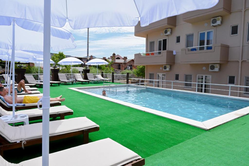 ein Hotel mit Pool, neben dem Leute auf Stühlen sitzen, ein Gebäude in der Unterkunft Max Kriti Hotel in Shëngjin