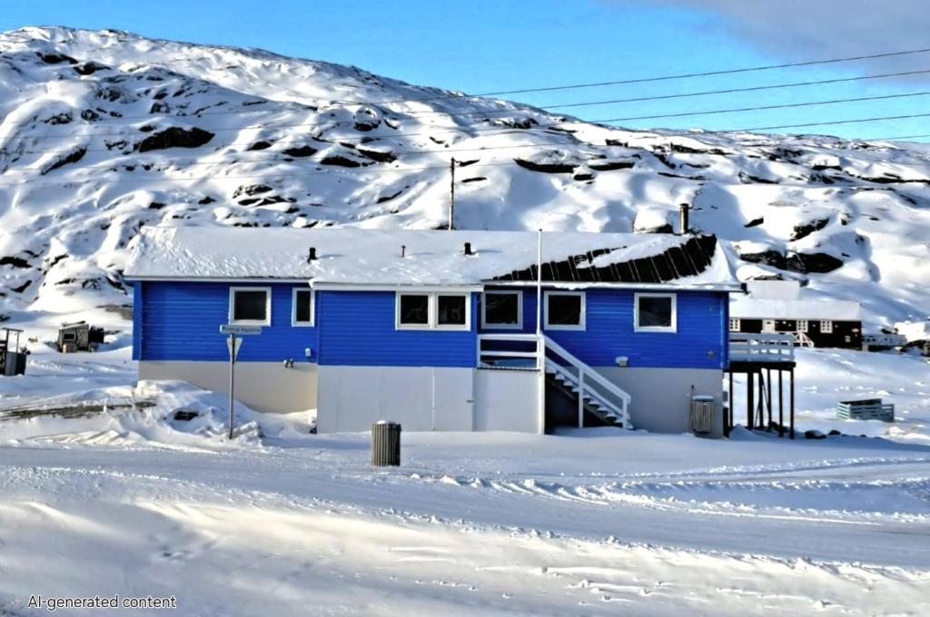a blue house in the snow with a snow covered mountain at Michelle's Blue House in Ilulissat