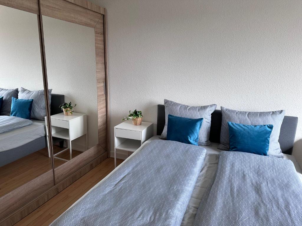 a bedroom with two beds with blue pillows and a mirror at CityZen Apartment CpH in Copenhagen