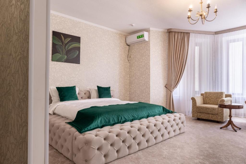 a bedroom with a large bed with a green blanket at Elit Garden Hotel in Kamianets-Podilskyi
