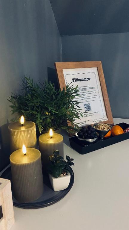 a table with three candles on a plate with a box at Bollnäs Lugn och Ro in Bollnäs