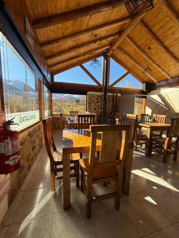 a dining room with wooden tables and chairs and windows at Gr Turismo in Los Molles