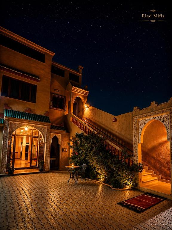 a building with a patio at night with a table at Riad Mifis in Rissani