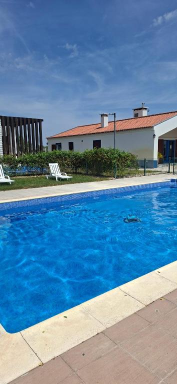 a blue swimming pool with two chairs and a building at Monte Beato in Almodôvar
