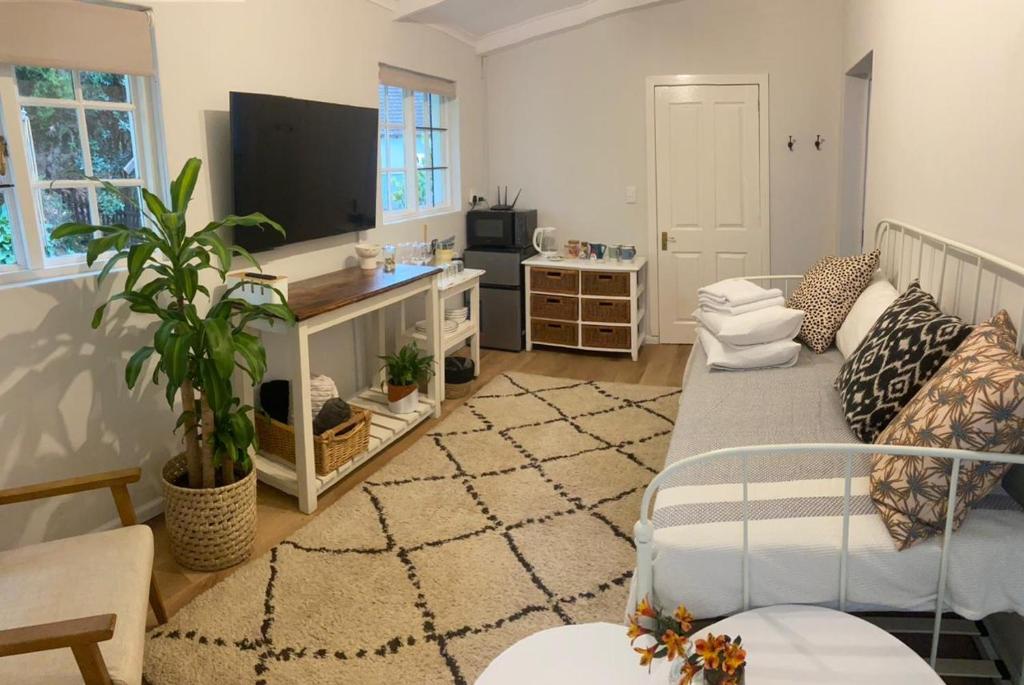a living room with a couch and a flat screen tv at Railway Cottage at Rawdons Country Estate in Nottingham Road