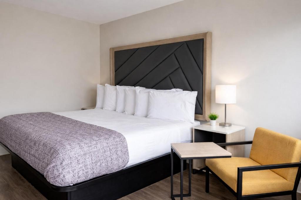 a hotel room with a large bed and a chair at Fair Motel in Upper Saddle River