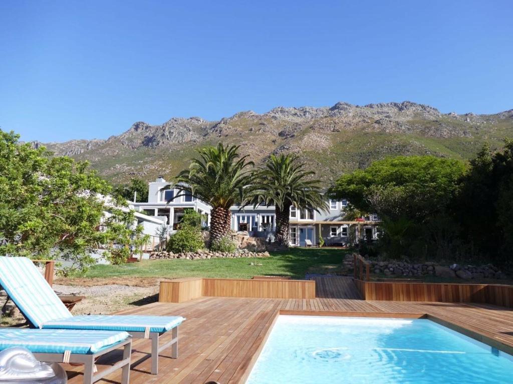 a house with a wooden deck and a swimming pool at Bloemenzee Boutique B&B in Gordonʼs Bay