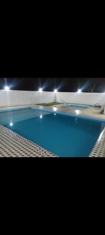 a large blue swimming pool with lights around it at Mir's Farm House in Hyderabad