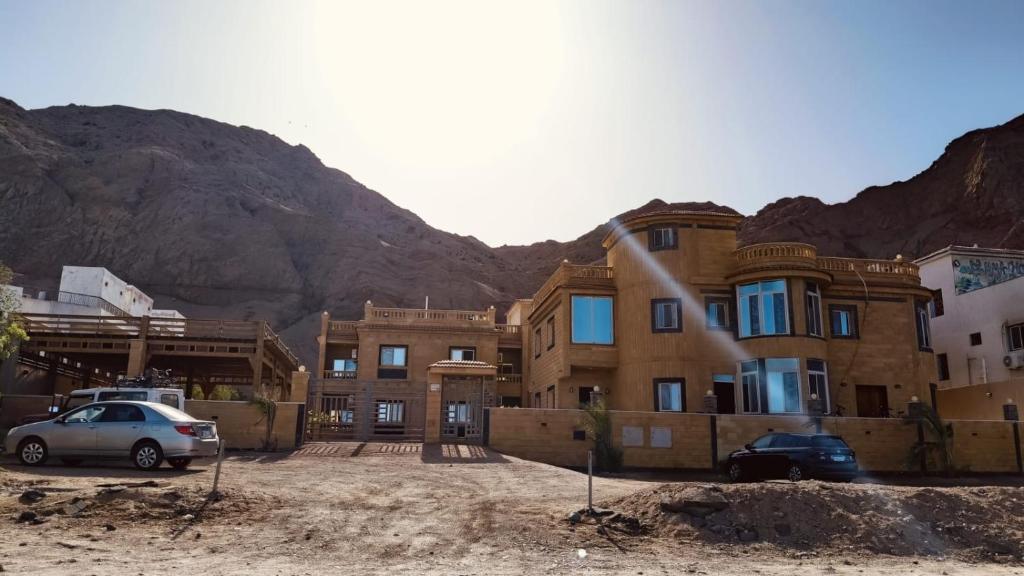 a building with cars parked in front of a mountain at The Palace Dahab in Dahab