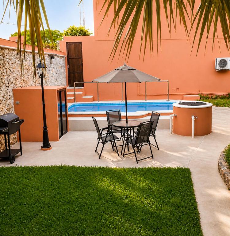 a patio with a table and chairs and an umbrella at Villa Odalys Cozy Mexican style house in Mérida