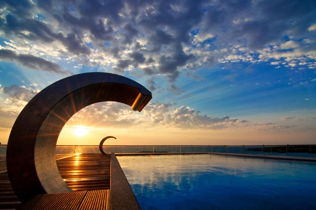 een zwembad met zonsondergang op de achtergrond bij Hotel Belvedere in Torre dell'Orso