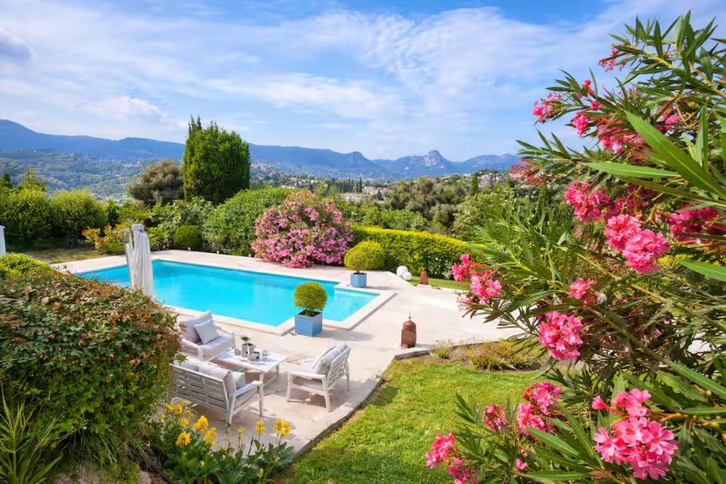 a garden with a swimming pool and flowers at Villa Del Sol with Mountain Views in Vence