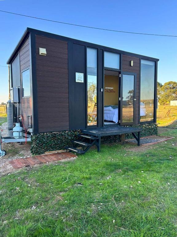 a tiny house with a bench in the grass at Ritaville by Tiny Away in Eaton
