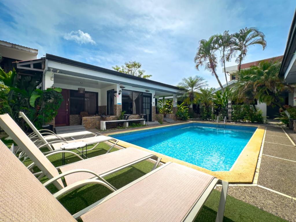 a swimming pool with chairs and a house at Ela Kosher Hotel and Synagogue in Jacó