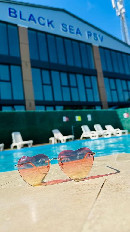 a pair of glasses sitting next to a swimming pool at Центральна Садиба in Kryzhanivka