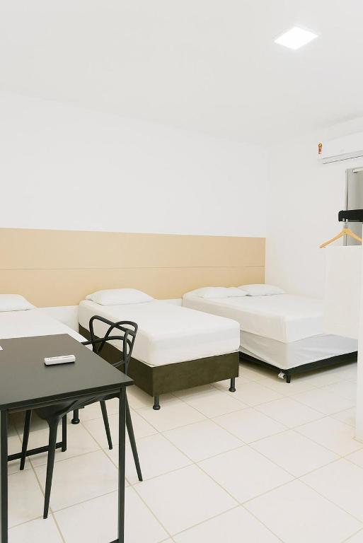 two beds in a room with a table and a chair at Villas Hotel in Barreiras