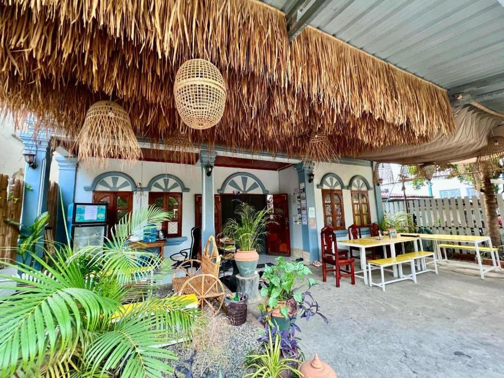 a patio with a table and chairs and a straw roof at La Casa Nostra in Luang Prabang