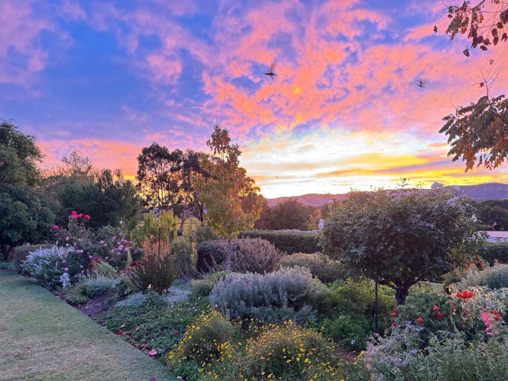 a garden with flowers and a sunset in the background at Barossa Garden Homestay in Williamstown