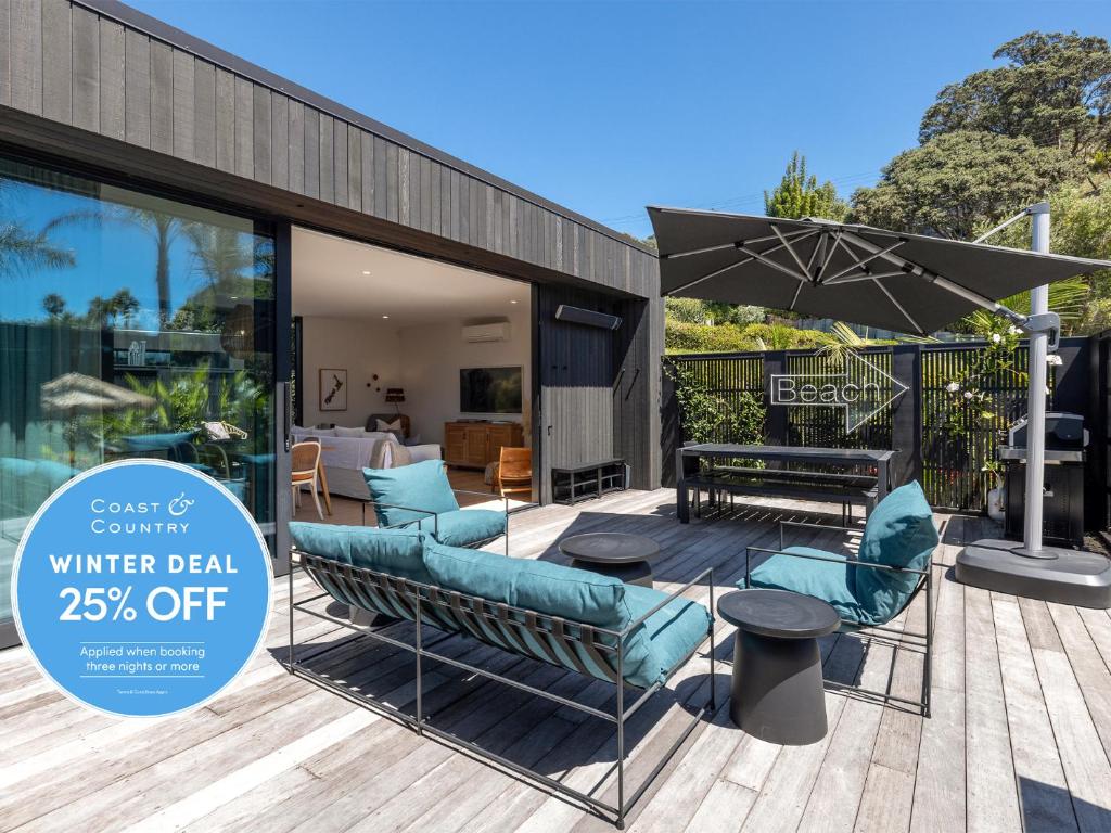 a patio with a table and chairs and an umbrella at Wavesong - Coast & Country in Onetangi
