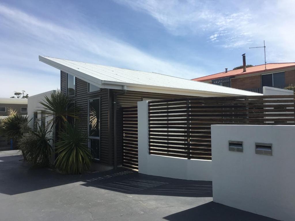 a house with a white fence and a building at Azure in Bridport