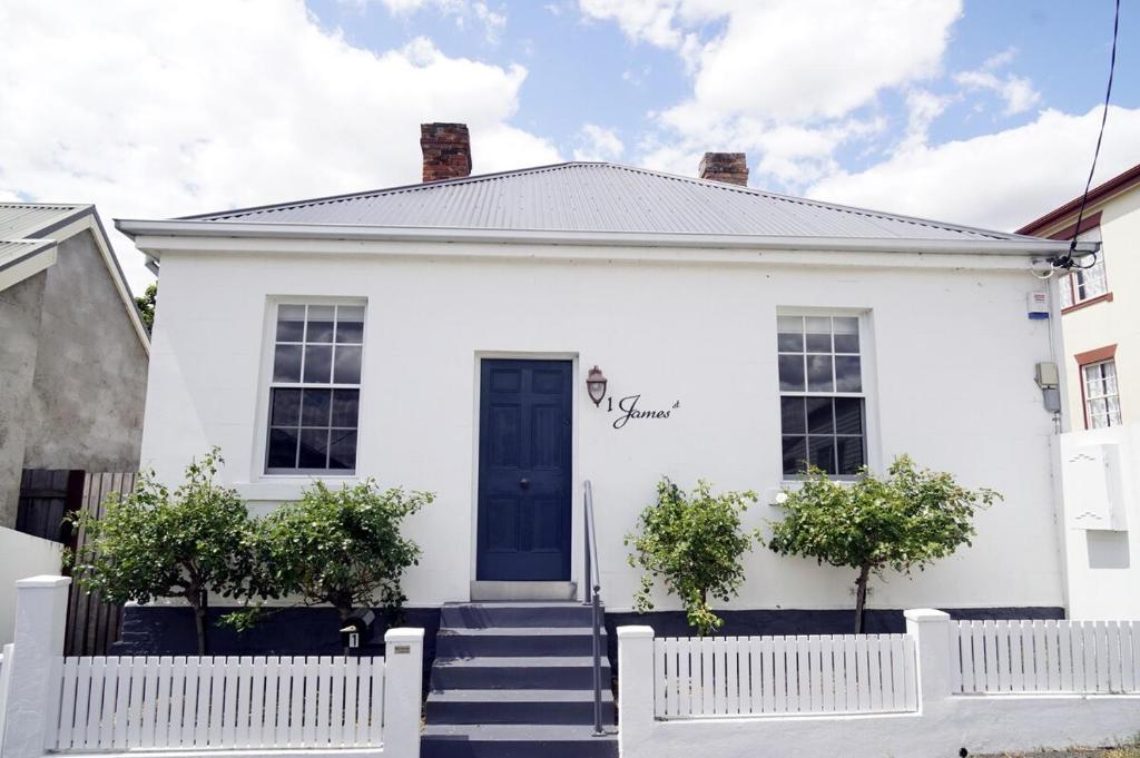 a white house with a blue door and stairs at Historic Getaway in Launceston