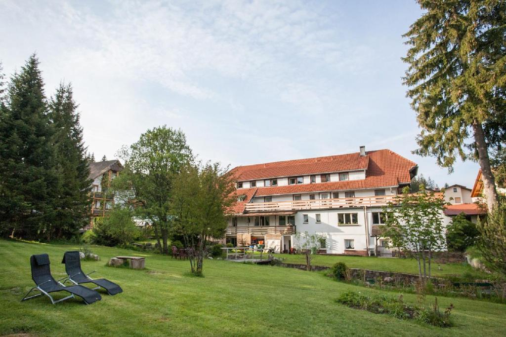 a group of blue chairs in the grass in front of a building at Pension Tannenheim in Schluchsee